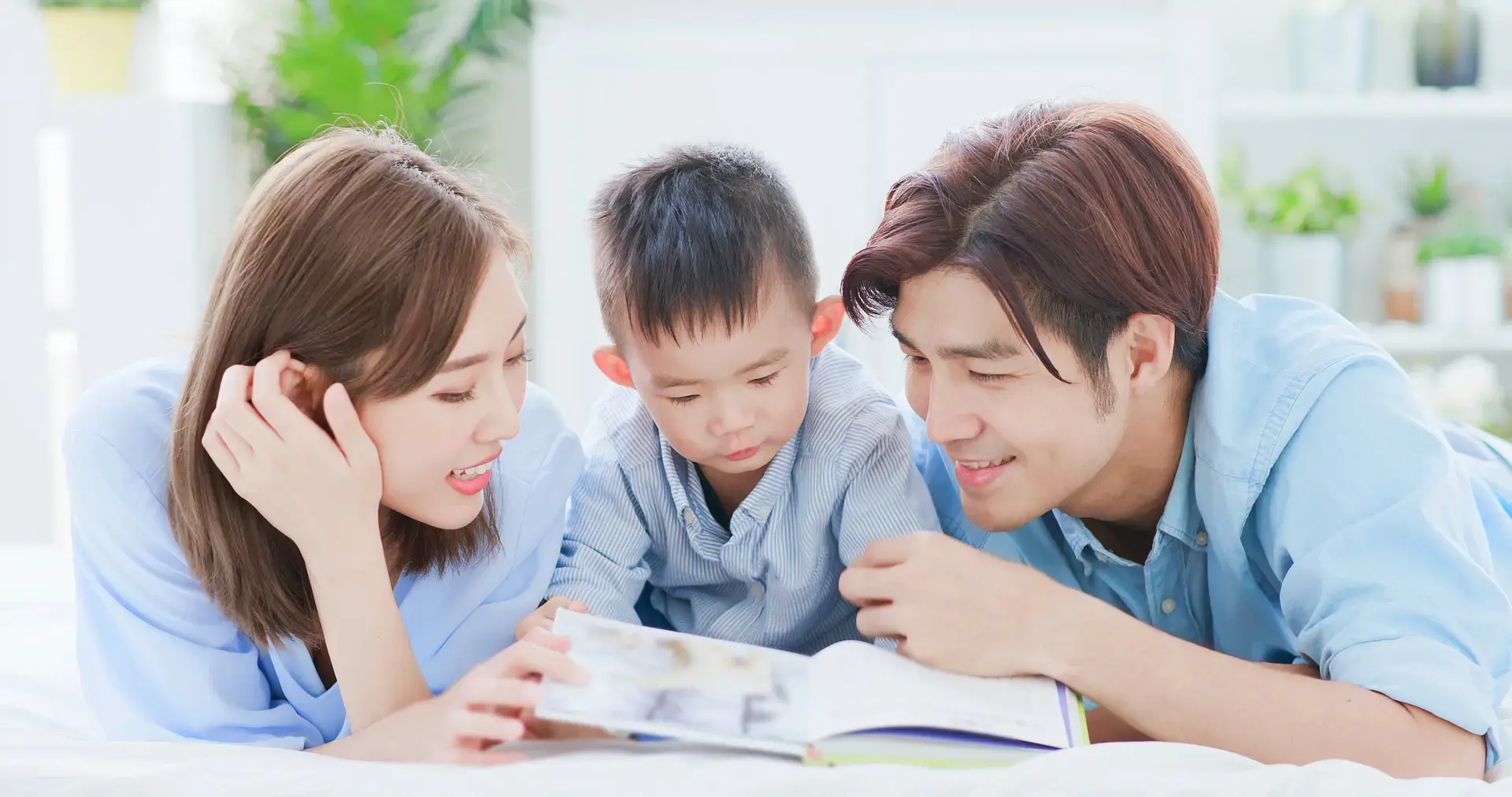 Asyanong pamilya na masayang nagbabasa ng libro.