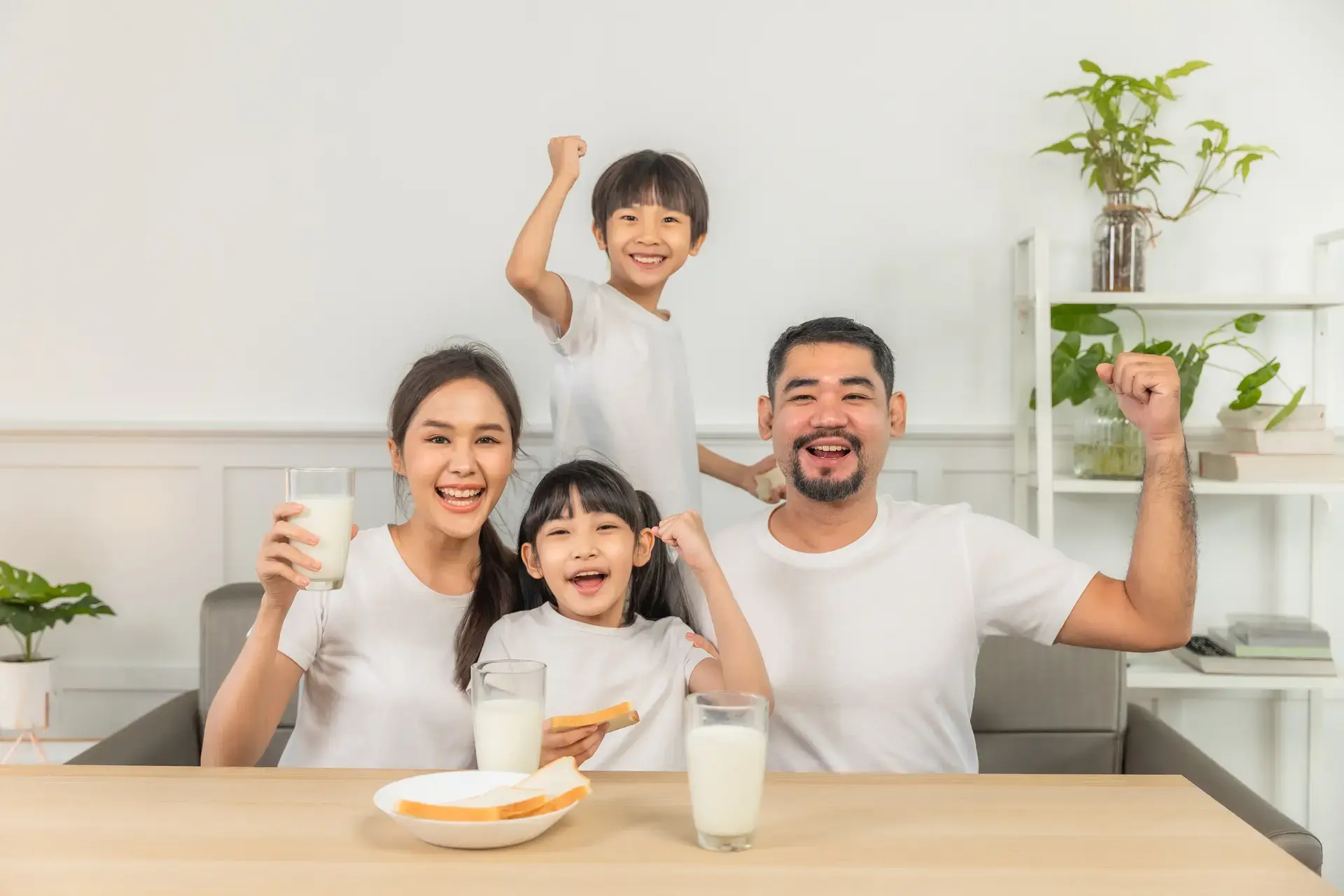 Isang pamilya na umiinom ng gatas at kumakain ng tinapay sa sala.